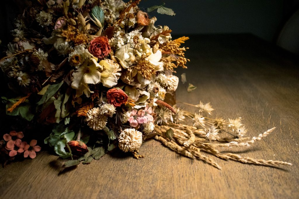 No words: a bouquet of dry, dead wedding flowers rests on a smooth, wooden floor