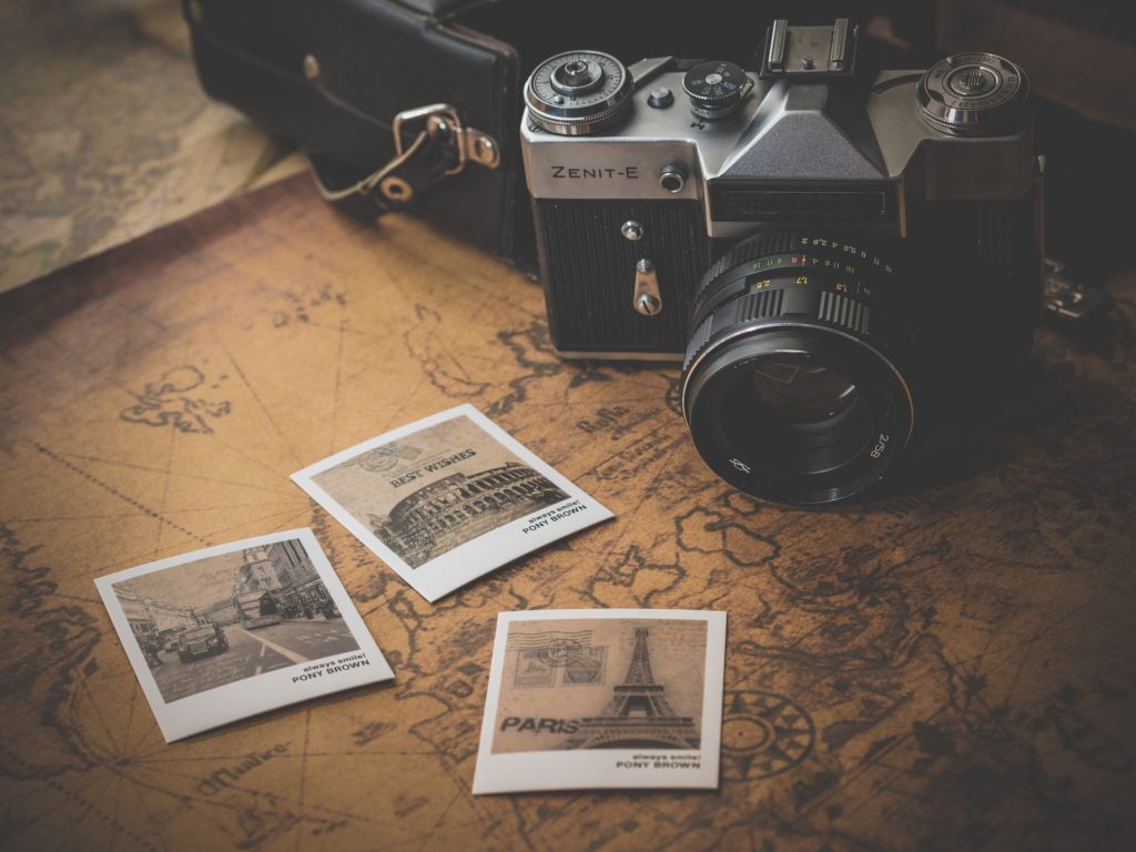see the world: a vintage camera and a few sepia photographs lay on an old world map