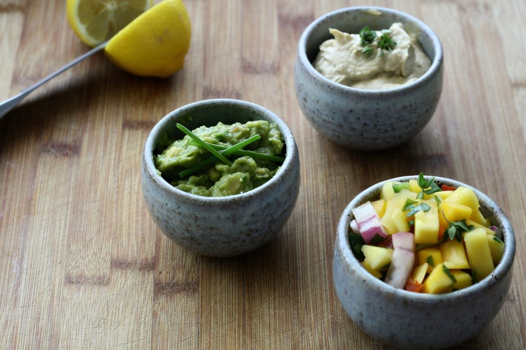 guacamole: three bowls of salsas sit on a wooden counter
